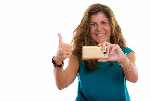 Mulher madura feliz sorrindo enquanto tira uma foto com seu telefone celular