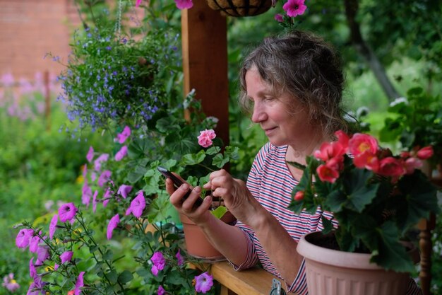 Mulher madura ligando no telefone e olhando flores