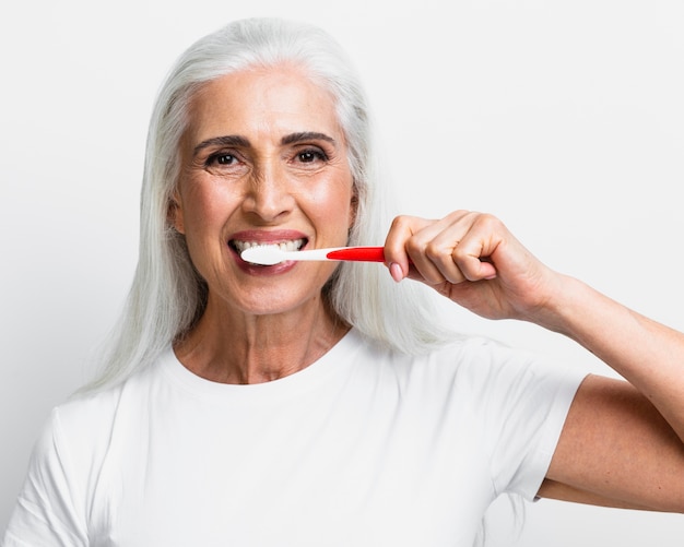 Foto mulher madura, limpar os dentes com escova de dentes