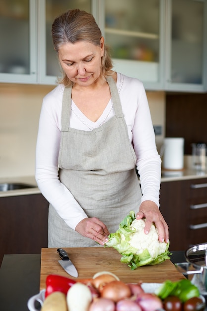 Mulher madura na cozinha preparando comida