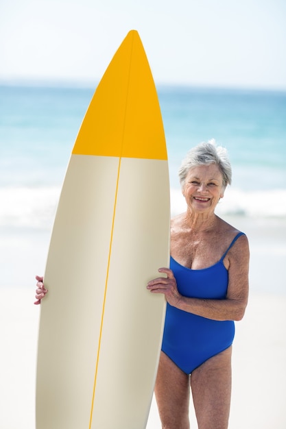 Mulher madura posando com uma prancha de surf