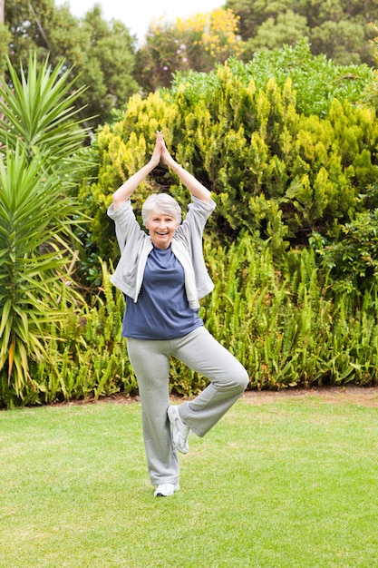 Mulher madura que faz seu streches no jardim