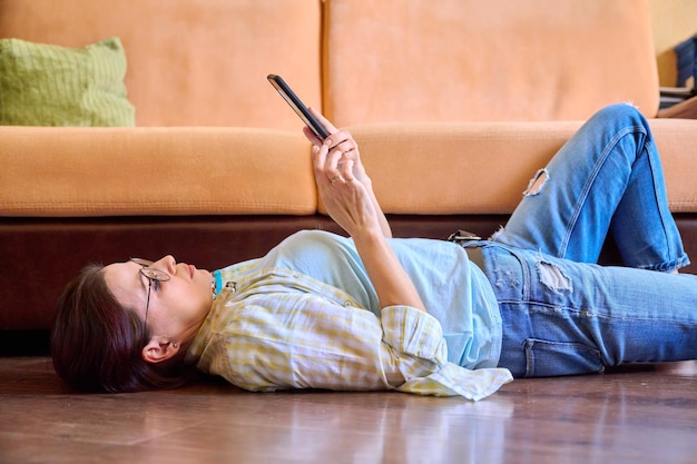 Mulher madura relaxando em casa usando smartphone