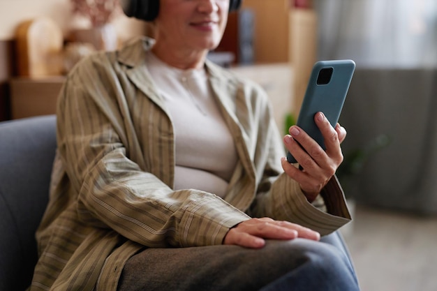 Mulher madura segurando um smartphone ouvindo música