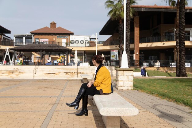 Mulher madura sentada em um banco em uma praça. Conceito de solidão.