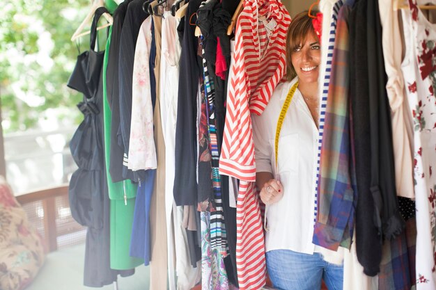 Foto mulher madura sorridente arranjando roupas em estantes na oficina