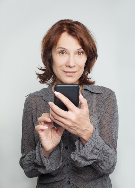 Mulher madura sorridente com telefone celular