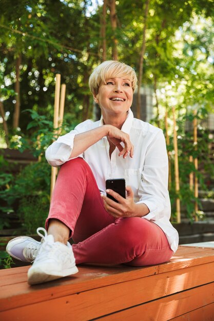 Mulher madura sorridente usando telefone celular