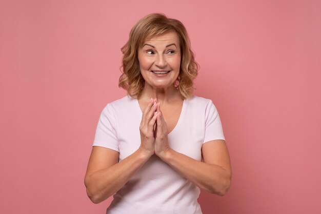 Foto mulher madura sorrindo no estúdio na parede rosa