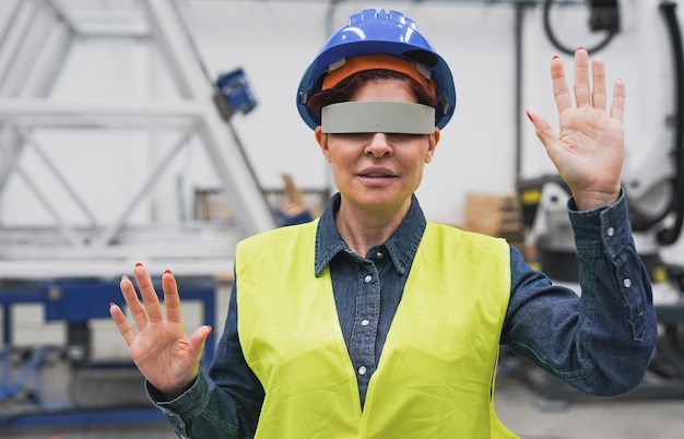 Mulher madura usando óculos de realidade virtual dentro da fábrica robótica