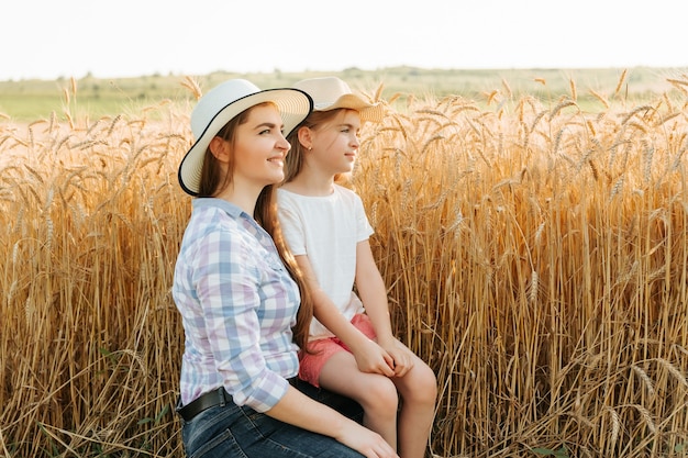 Mulher mãe e filho, a filha dela na área rural, perto da família do campo de trigo dos agricultores vista lateral de mo ...