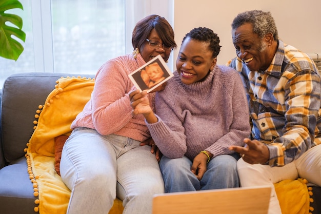 Mulher mãe solteira mostrando a ultrassonografia virtualmente com seus pais orgulhosos