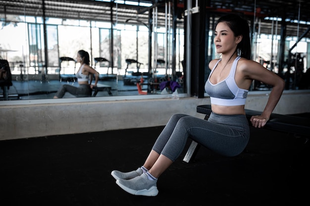 Mulher magra asiática joga tríceps no ginásio