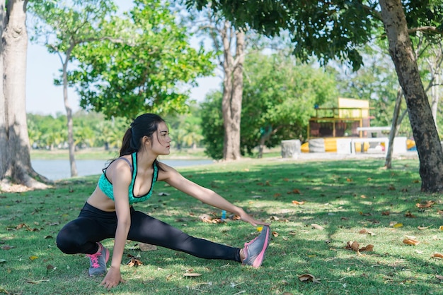 Mulher magra asiática se aquece antes do trabalho para se exercitar para a vida, povo da Tailândia Esticando o corpo antes de correr