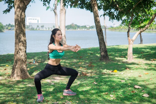 Mulher magra asiática se aquece antes do trabalho para se exercitar para a vida, povo da Tailândia Esticando o corpo antes de correr