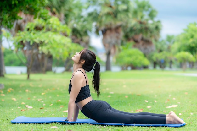 Mulher magra asiática se exercita sozinha no parqueCansada do treinoJogar conceito de ioga