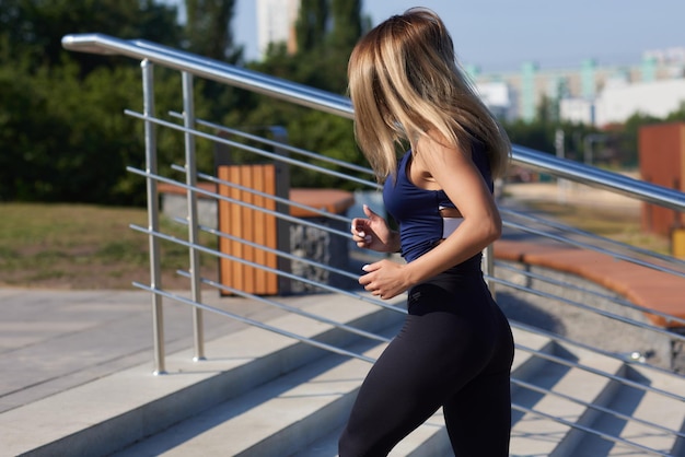 Mulher magra atlética em um dia ensolarado corre ao longo do aterro ou parque