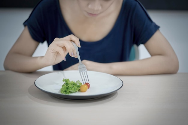 Mulher magra comendo salada de pequena porção