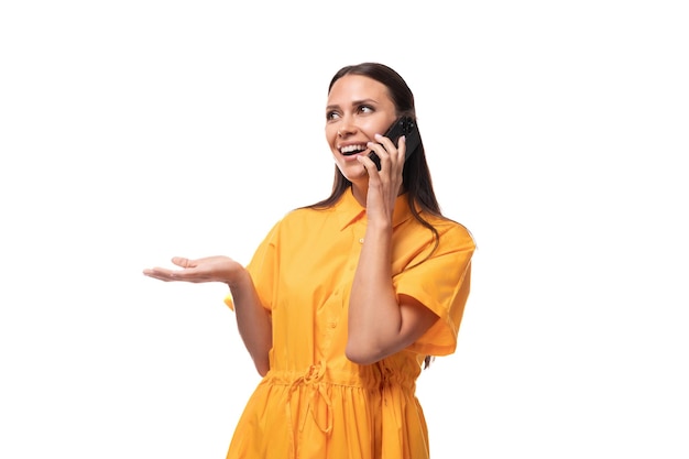 Foto mulher magra de cabelos pretos vestida com um vestido laranja fala ao telefone