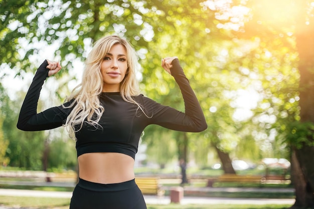 Mulher magra em pé e mostrando o corpo do lado de fora do parque verde pela manhã olhando para a câmera