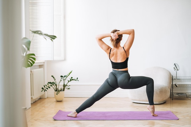 Mulher magra em roupas esportivas fazendo exercícios de fitness na sala de estar em casa
