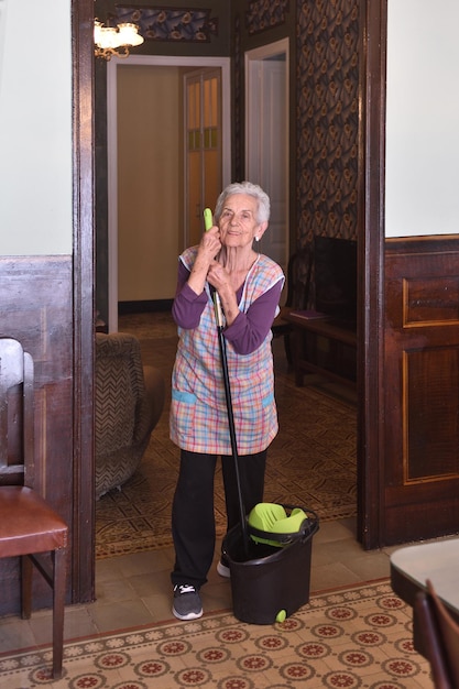 Foto mulher mais velha com esfregão fazendo o chão de sua casa