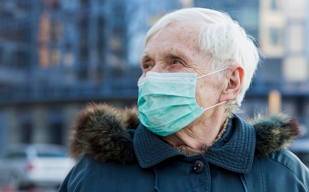 Mulher mais velha com máscara médica na cidade