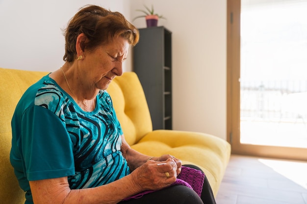 Mulher mais velha tricotando sentada no sofá