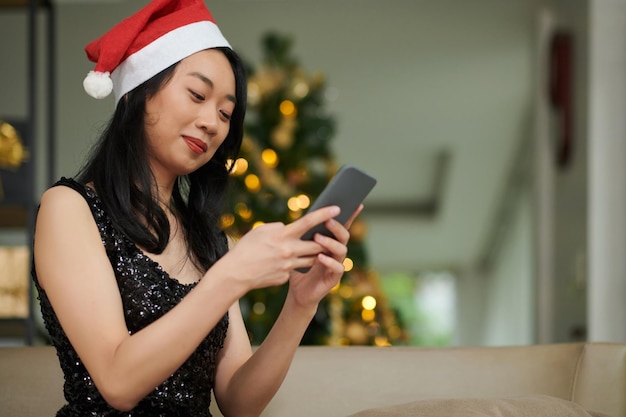 Mulher mandando mensagens de texto para amigos na véspera de Natal