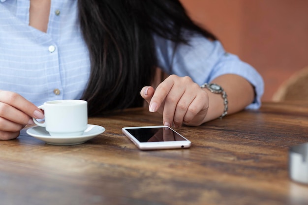 Mulher mão café e telefone no café