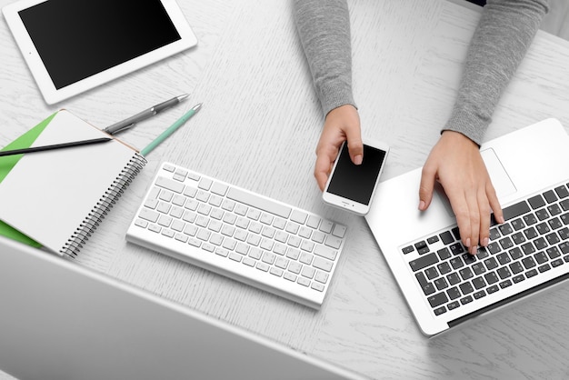 Mulher mãos na mesa com computador tablet smartphone e outras coisas vista superior