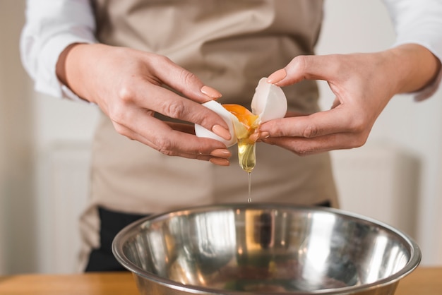 Mulher, mãos, quebrar, um, ovo, para, ovo branco separado, e, yolks