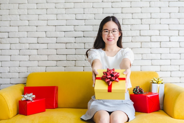 Mulher, mãos, segurando, amarela, giftbox, com, laço vermelho, dar, presente