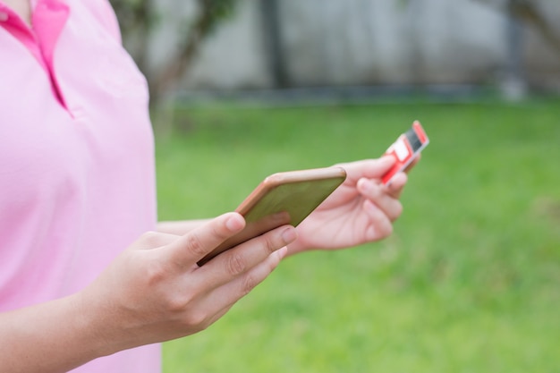 Mulher mãos segurando um cartão de crédito e usando celular, telefone inteligente para compras on-line