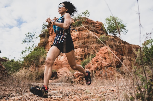 Foto mulher maratonista de ultra trilha correndo pela montanha rochosa