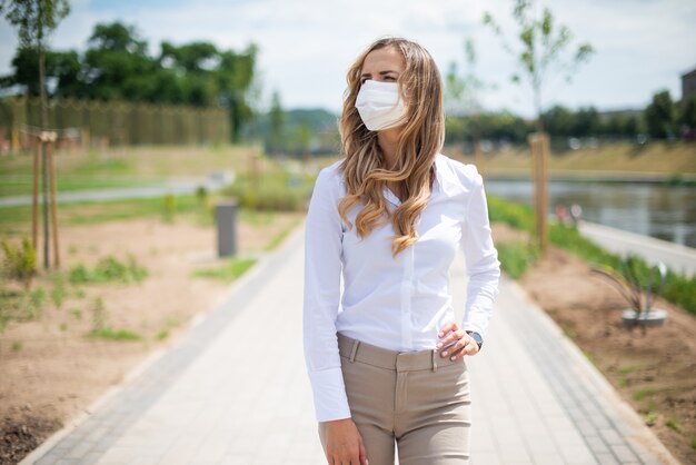 Mulher mascarada caminhando em um parque da cidade durante emergência de coronavírus