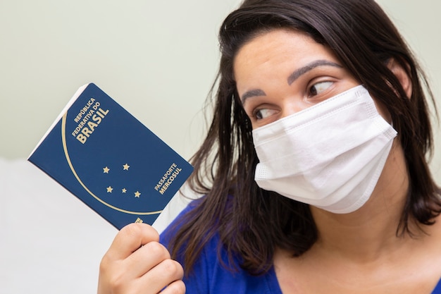 Foto mulher mascarada com passaporte brasileiro na mão.