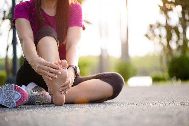 Mulher massageando seu pé doloroso durante o exercício. Conceito de lesão do esporte.