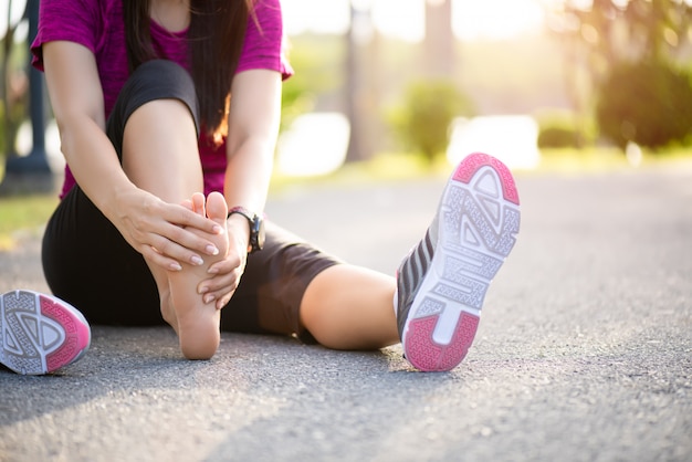 Mulher massageando seu pé doloroso durante o exercício. Executando o conceito de lesão do esporte.