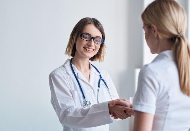 Mulher médica aperta a mão de paciente em camiseta branca