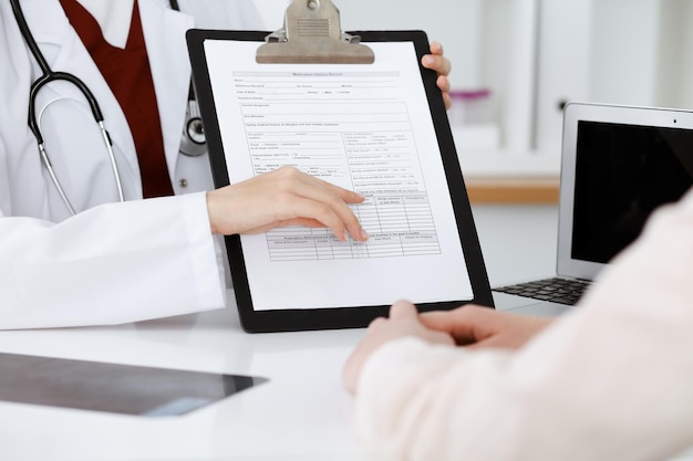 Mulher-médica desconhecida consultando paciente e usando prancheta com registro de histórico de medicação. Conceito de medicina.