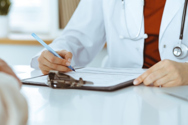 Mulher-médica desconhecida consultando paciente e usando prancheta com registro de histórico de medicação. Conceito de medicina.