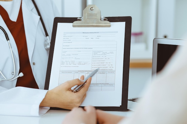 Mulher-médica desconhecida consultando paciente e usando prancheta com registro de histórico de medicação. Conceito de medicina.