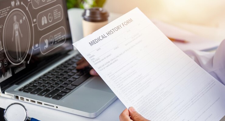 Foto mulher médica digitando informações da prescrição do paciente do formulário de histórico médico da papelada no laptop