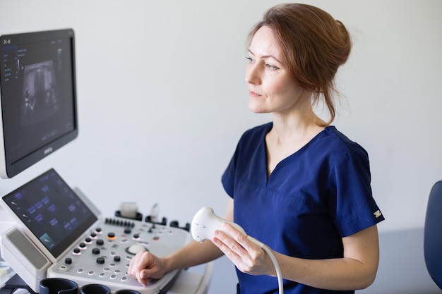 Foto mulher médica em uniforme sentada no escritório em um hospital com equipamento de máquina de diagnóstico por ultrassom e pronta para examinar pacientes fazendo ultrassom da glândula tireóide diagnóstico por ultrassom