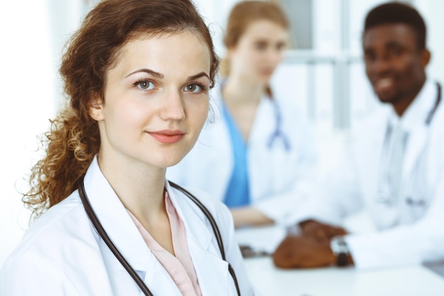 Mulher médica feliz com equipe médica no hospital. Grupo de pessoas multiétnicas.