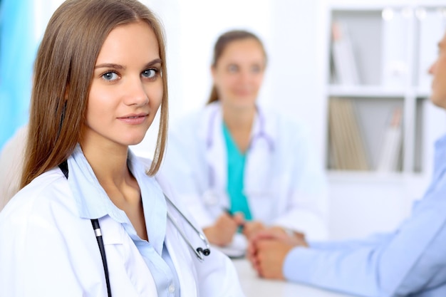 Mulher médica feliz com equipe médica no hospital sentado à mesa e discutindo a história médica