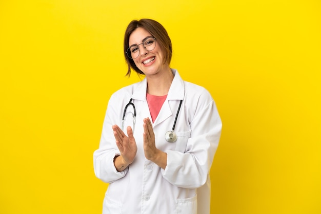 Mulher médica isolada em fundo amarelo aplaudindo após apresentação em conferência