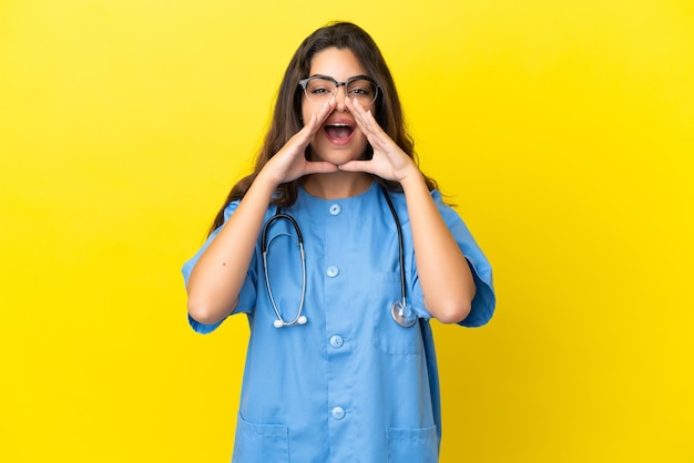 Mulher médica jovem cirurgião isolada em fundo amarelo gritando e anunciando algo