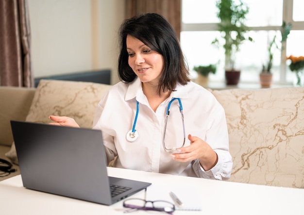 Mulher médica on-line consulta um paciente faz videoconferência de uma webcam em um laptop